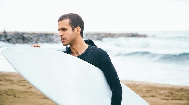 Foto ritratto di un surfista sulla spiaggia contro il cielo