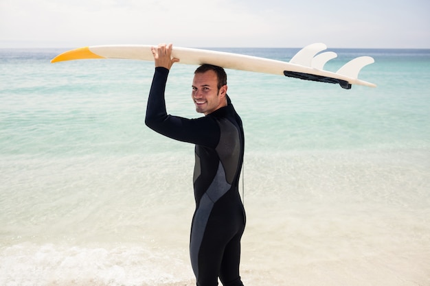 Portrait of surfer holding surfboard over head