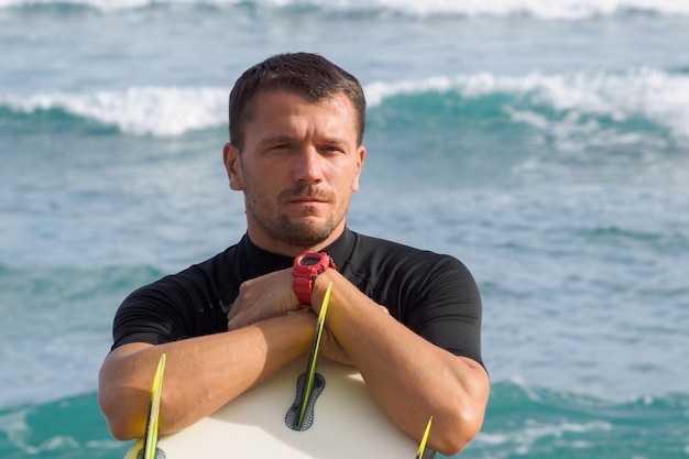 Portrait of a surfer holding a surfboard. Ocean .