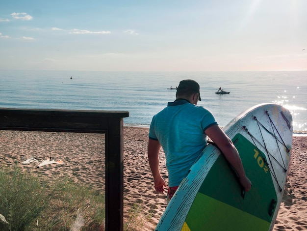 해변에서 SUP 보드와 서퍼의 초상화 바다 익스트림 스포츠 개념에 젊은 남자