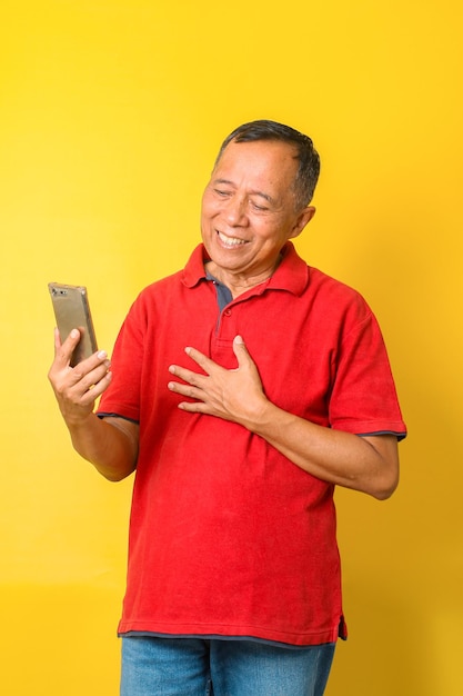 Portrait of surprised Asian senior man looking smart phone and hand on chest Human face expressions