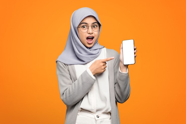Portrait of surprised beautiful Asian woman pointing to smartphone