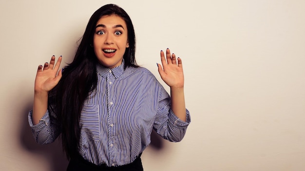 Portrait of surprised beautiful girl in casual wear with raised arms