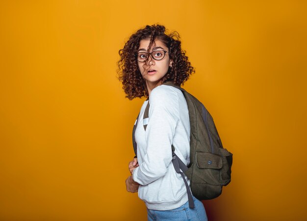 Portrait of a surprised Indian female student girl in glasses with a backpack. 