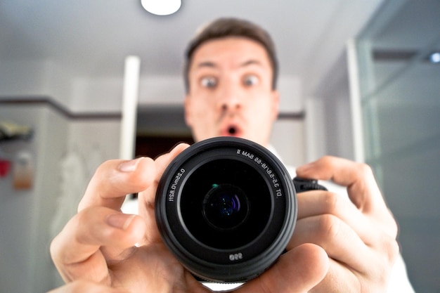 Photo portrait of surprised man holding camera