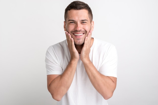 Portrait of surprised man in white t-shirt standing against plain background