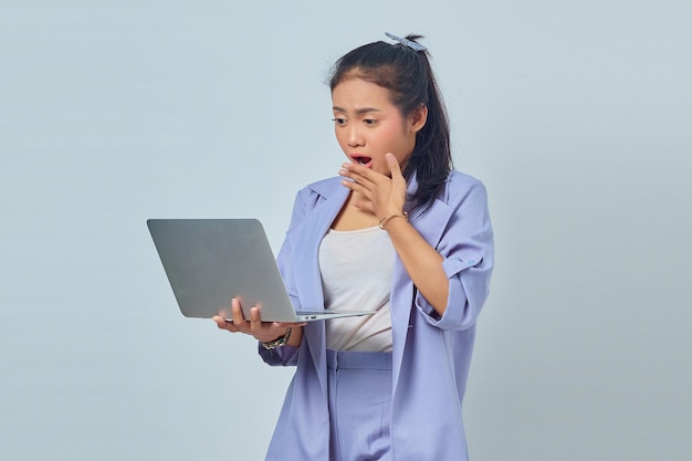 Portrait of surprised young Asian business woman looking at incoming email on laptop isolated on white background