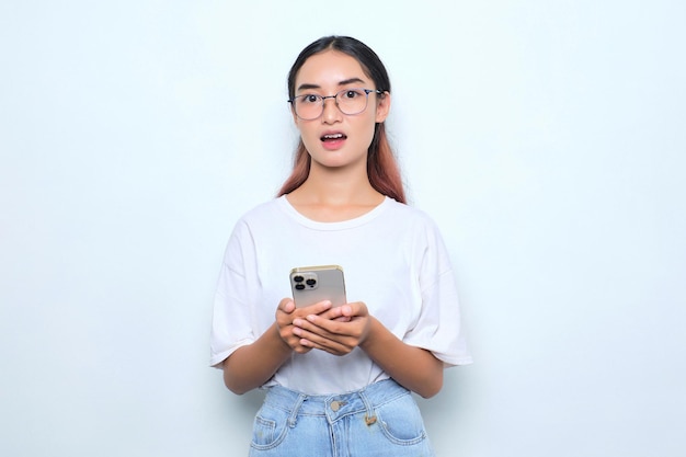 Portrait of surprised young Asian girl in white tshirt using mobile phone isolated on white background