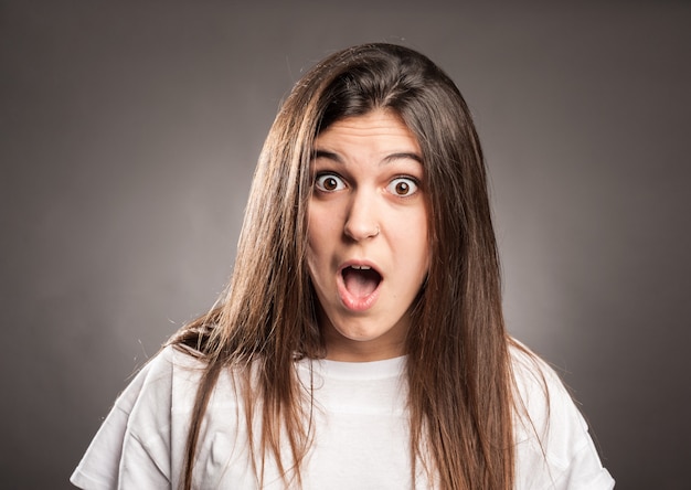 Portrait of surprised young girl on gray