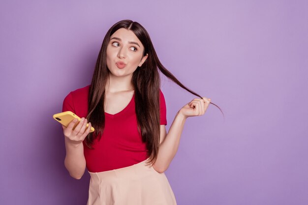 Portrait of sweet lovely romantic lady hold phone play curl look empty space on violet background