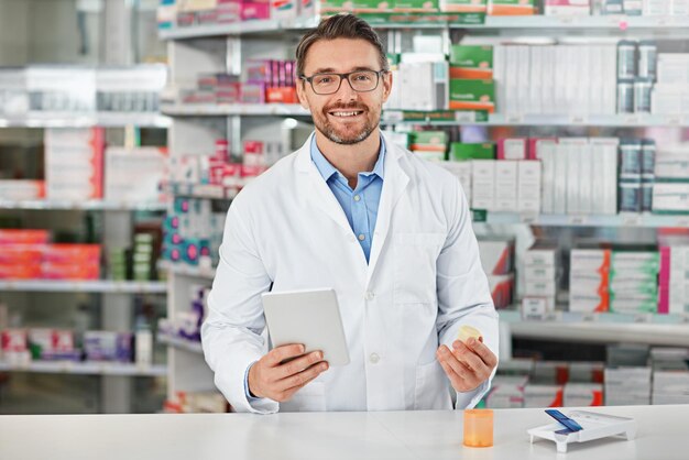 Portrait tablet and healthcare with a pharmacist man at work in a pharmacy for pharmaceutical medication Medicine trust and pills with a male working in a medical dispensary for treatment or cure