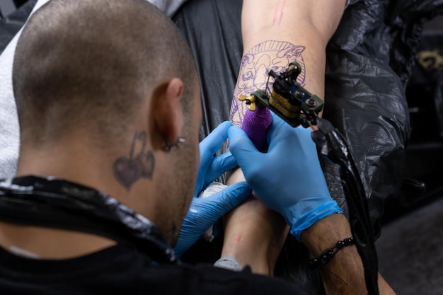 Portrait of a tattoo artist with an alternative profile at work tattooing a client39s leg in his small studio small business