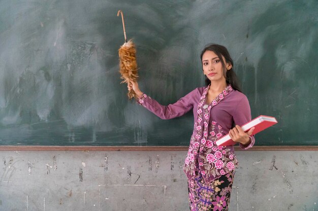 Photo portrait of teacher standing against blackboard in classroom