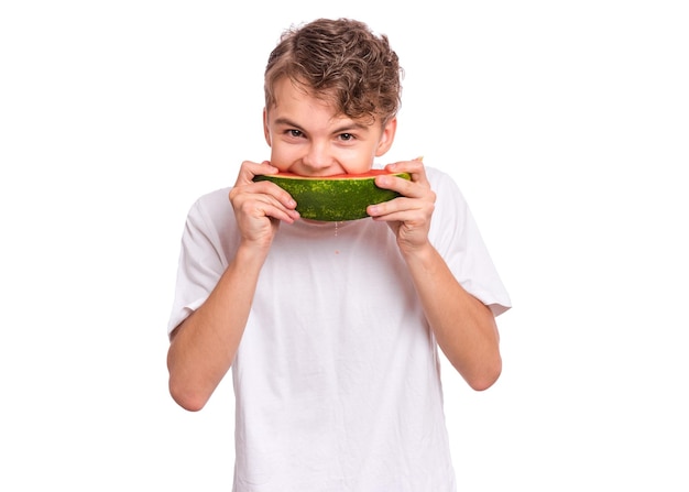 Portrait of teen boy eating ripe juicy watermelon and smiling Cute caucasian young teenager with slice healthy watermelon Funny happy child wearing white tshirt isolated on white background