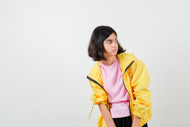 Portrait of teen girl looking aside in t-shirt, jacket and looking shocked front view