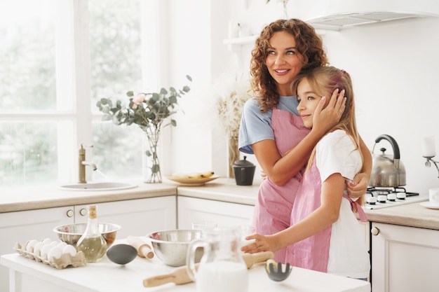 Portrait of a teen girl with her mother at home in kitchen