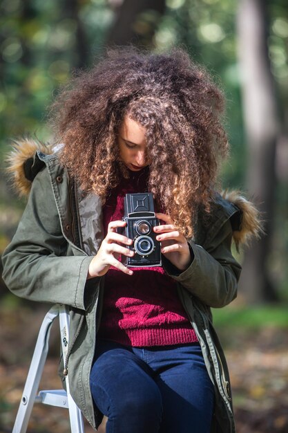 Portrait of teen girl with retro camera taking photos in nature