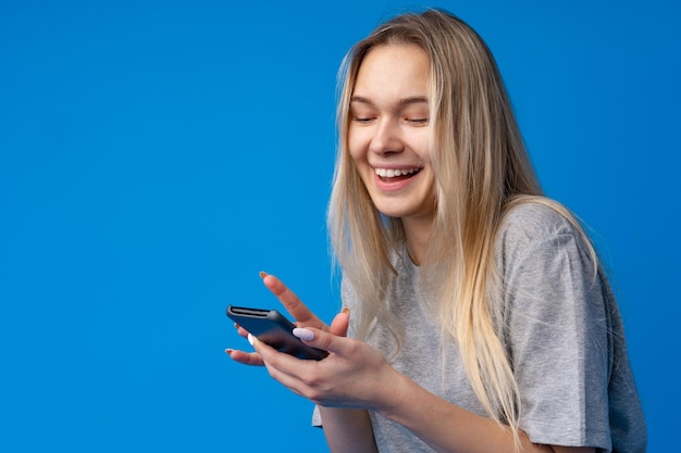 Portrait of a teen young girl using smartphone over blue background