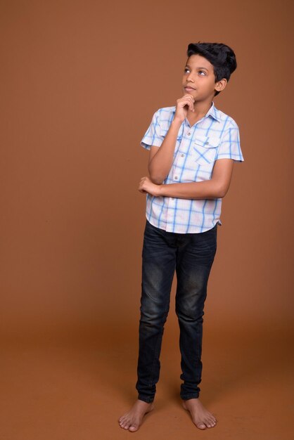 Portrait of teenage boy standing against orange background