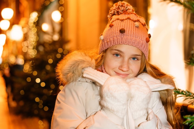 Portrait teenage girl on festive evening outdoors in winter holds her hands