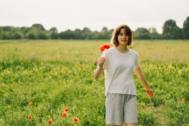 Portrait Of Teenage Girl Happy Cheerful Teen Girl With Pronounced Face dancing In Outdoors in a field with red poppies