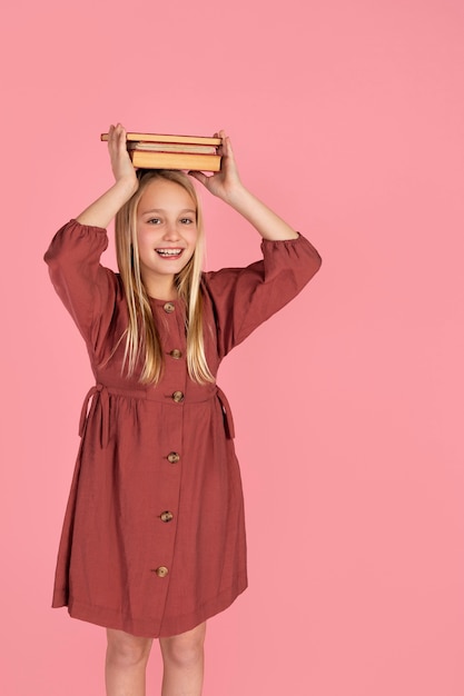 Foto ritratto di ragazza adolescente con libri sulla testa e sorridente