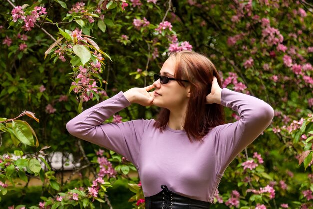 写真 咲くリンゴの木の春の公園を歩くサングラスの肖像画の10代の少女