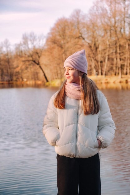 屋外の湖のある秋の公園でカジュアルな秋の服を着て目をそらしている肖像画の10代の少女