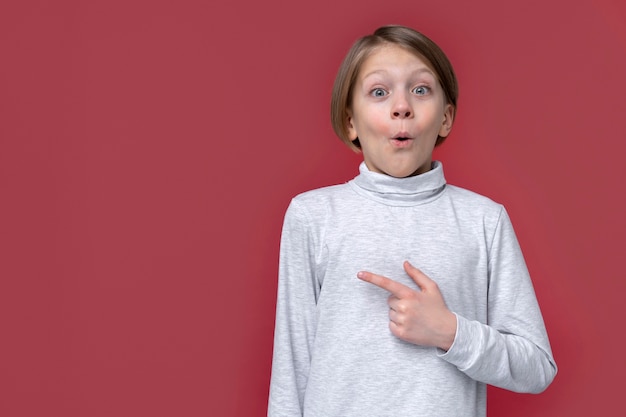 Photo portrait of teenage girl looking surprised and pointing to the left