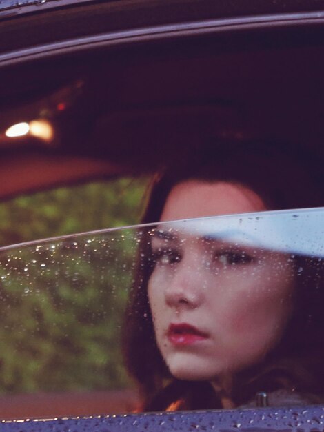 Photo portrait of teenage girl looking through wet window during rainy season