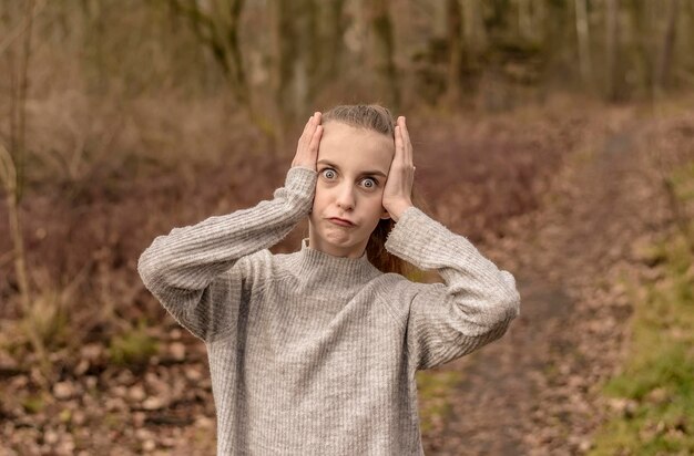 Portrait of teenage girl making face while standing in forest