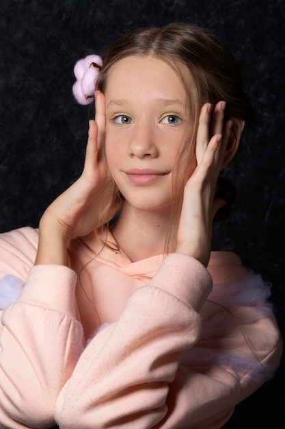 Portrait of a teenage girl in pink clothes on a dark background.