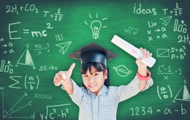 Portrait of teenage girl showing thumbs up with certificate against formulas on blackboard