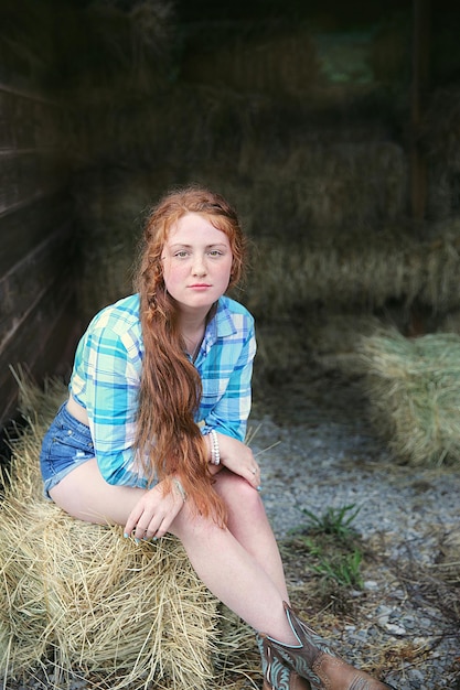 Portrait of teenage girl sitting on hay bale