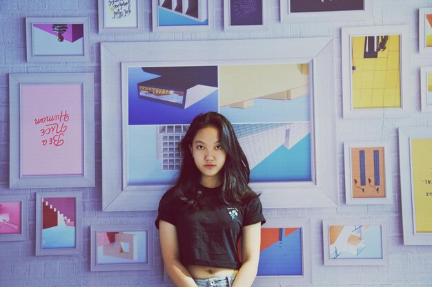 Photo portrait of teenage girl standing against frames