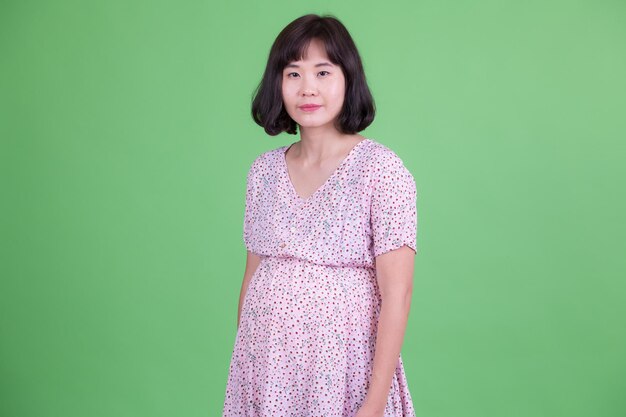 Portrait of teenage girl standing against green background