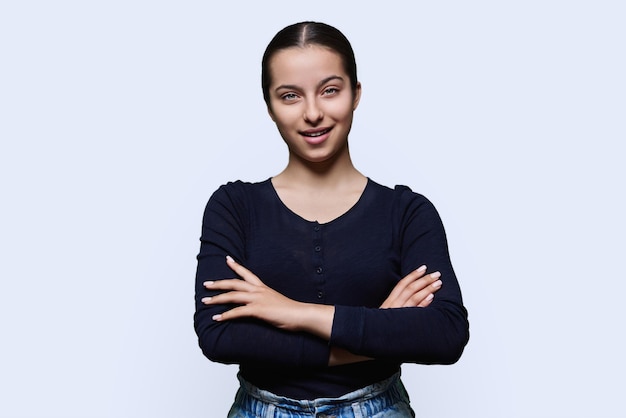 Photo portrait of teenage smiling female looking at camera on light background