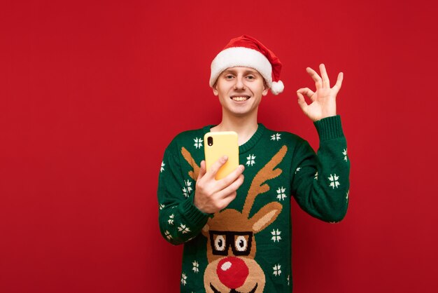 Foto ragazzo dell'adolescente del ritratto con il telefono della tenuta del maglione di natale