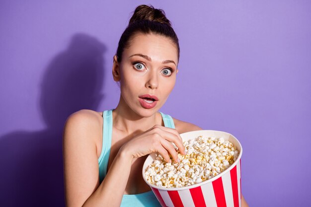 portrait of terrified girl eating corn watching thriller genre film