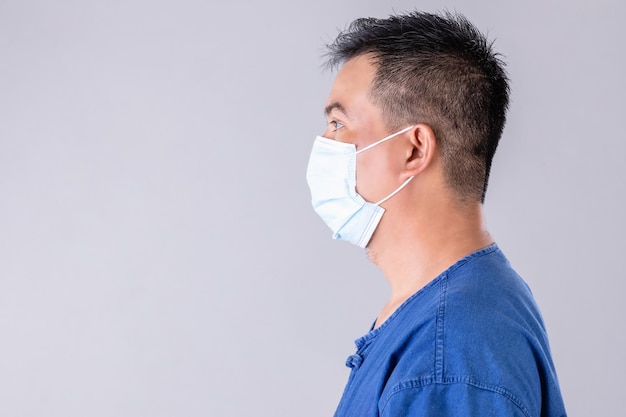 灰色の背景で撮影されたウイルスを防ぐために保護面膜を着用したタイの農家の肖像画