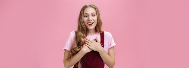 Portrait of thankful and pleased happy young girl receiving surprise gift on bday pressing palms to 