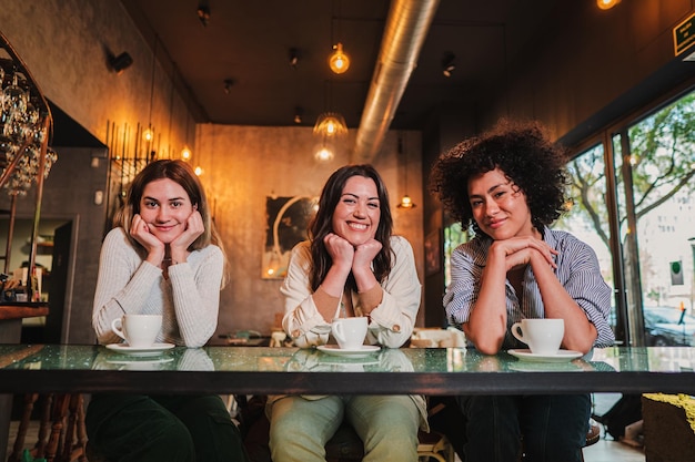 Portrait of thee young women smiling and posing looking at camera on a coffee shop Photo of a group of happy females on a restaurant or bar