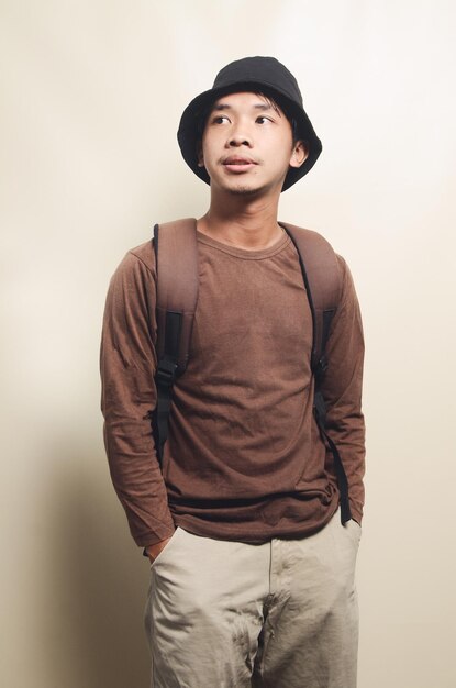 Портрет думающего молодого азиатского мальчика с рюкзаком на заднем плане