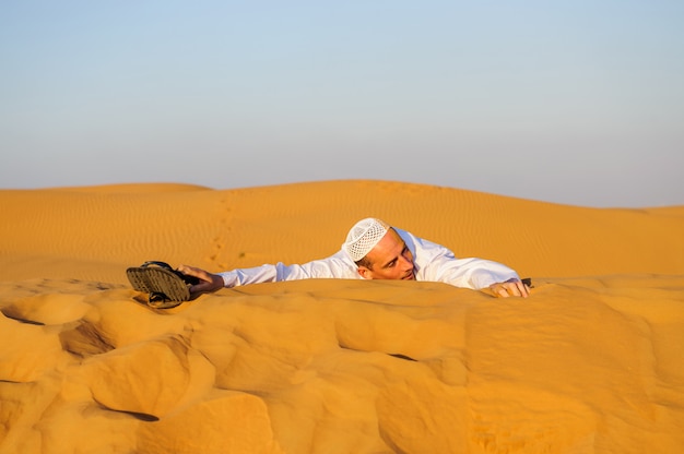 Portrait of thirsty Arabic man on a middle of yellow desert.