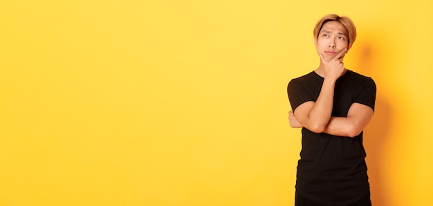 Portrait of thoughtful attractive guy in black tshirt looking upper left corner young man pondering ...