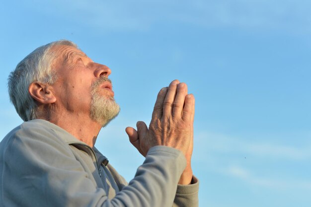 Portrait of thoughtful elderly man praying  on yellow autumn background