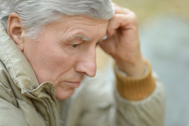 Portrait of thoughtful elderly man on yellow autumn background