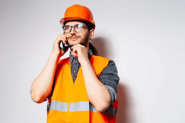 Portrait of thoughtful engineer talking on smartphone on white background