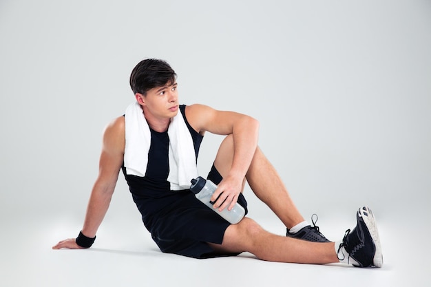 Portrait of a thoughtful fitness man resting on the floor isolated