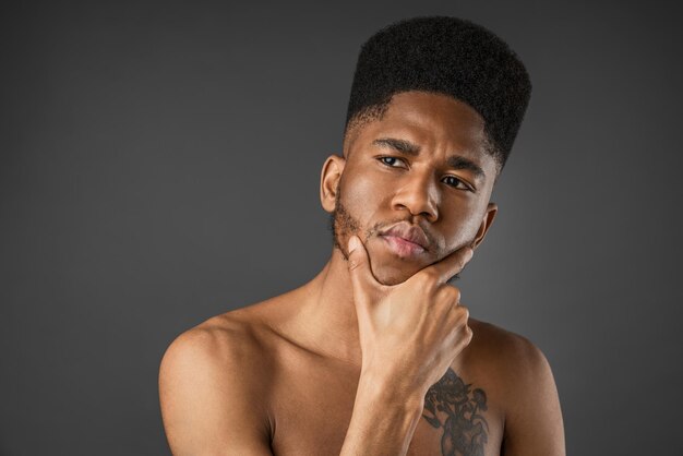 Portrait of thoughtful half naked young man isolated over dark gray background